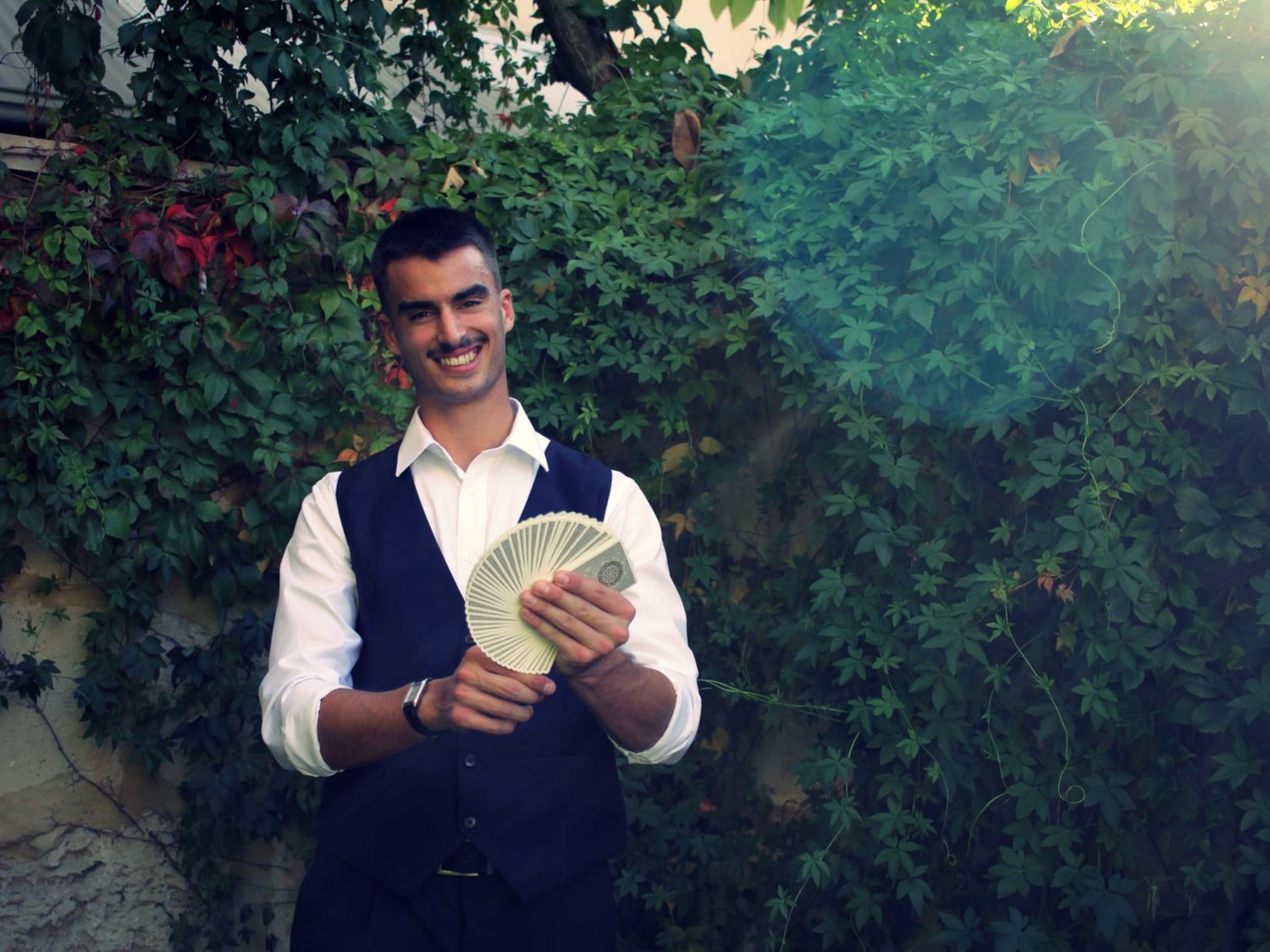 Dominic Miles smiling and fanning a deck of cards