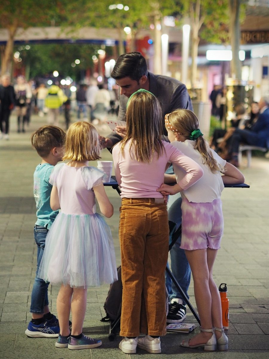 Dominic performing close-up magic for children at a market